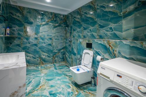 a blue tiled bathroom with a washing machine at Kotarja Apartments in Dhërmi