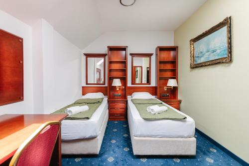 a hotel room with two beds and a desk at Vila Sentandreja in Subotica