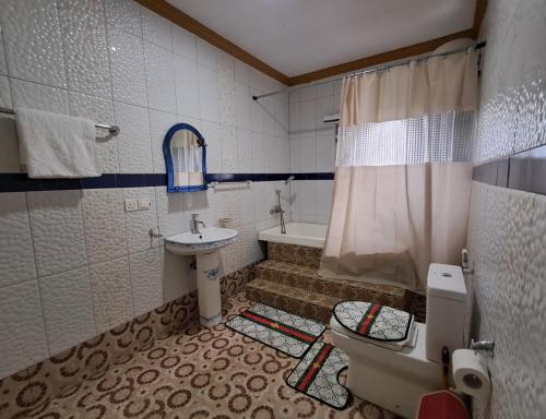 a bathroom with a sink and a toilet and a tub at Immanuel Victory Hotel & Restaurant in Ajenkotoku