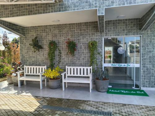 two benches in front of a store with plants at Hotel Rota do Sul in Juquiá