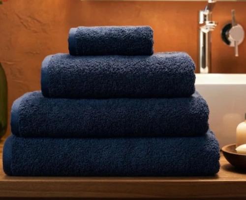 a stack of blue towels on a table next to a bath tub at Strandhaus Adria in Ulcinj