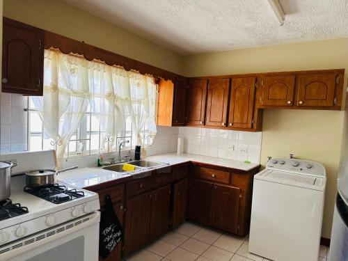 a kitchen with wooden cabinets and a white stove top oven at Guest house 2 in Upper Conaree
