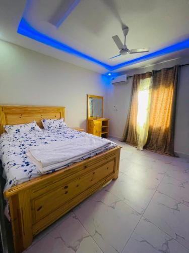 a bedroom with a large bed with a blue ceiling at Sowe's Villa in Old Yundum