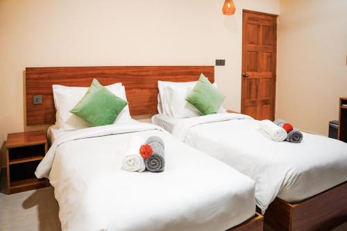 a bedroom with two beds with white sheets and green pillows at Naeco Select Pearl in Hanimaadhoo