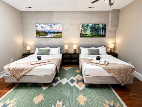 two beds in a bedroom with two lamps and a rug at Historic Main St Apt | Private Garage in St. Charles