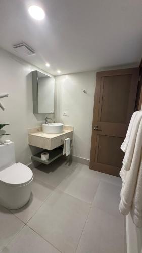 a white bathroom with a toilet and a sink at Xanadu Casa De La Playa in Puerto Plata