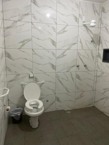 a bathroom with a toilet and a tiled wall at Espaço Vida Nova in Lins
