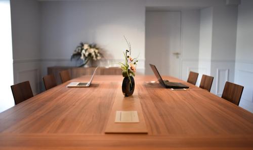a long wooden table with a vase with flowers in it at Hôtel du Cheval Blanc - Paris Marne La Vallée in Jossigny
