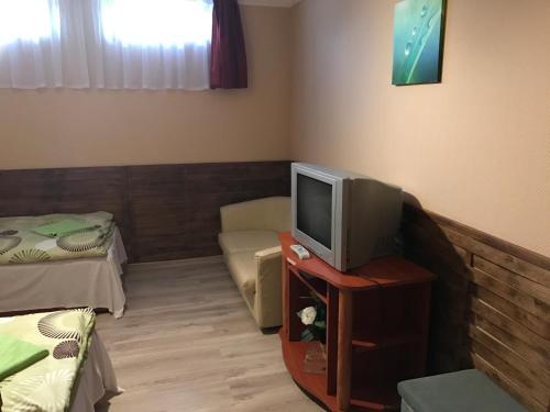 a room with a tv on a table with a couch at Abszolút Hotel és Panzió in Nyírbátor