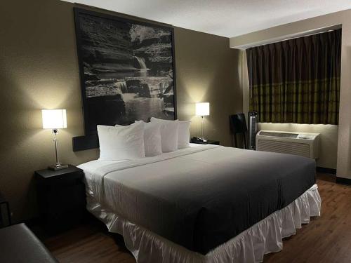 duże łóżko w pokoju hotelowym z dwiema lampami w obiekcie Super 8 by Wyndham Ithaca w mieście Ithaca