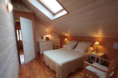 une chambre avec un lit blanc et une lucarne dans l'établissement Maison Au Jardin, à Biscarrosse