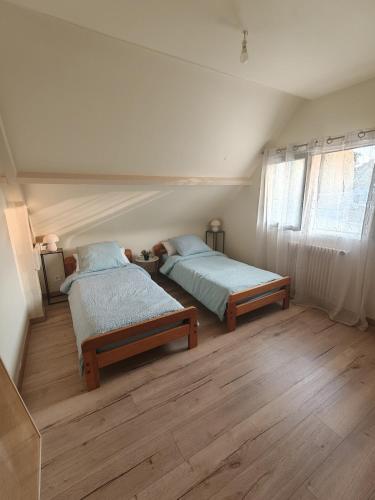 two beds in a bedroom with wooden floors at Maison de charme 209m2 in Coray