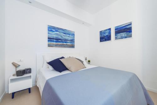 a white bedroom with a bed and a night stand at Puolo Seaside Apartment in Massa Lubrense