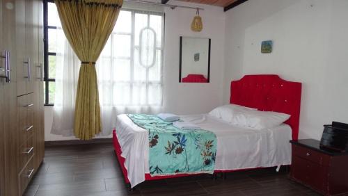 a bedroom with a bed with a red headboard at Valso Posada Campestre in Silvania
