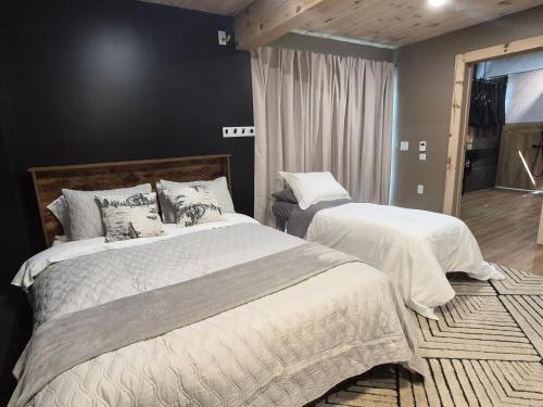 a bedroom with two beds with white blankets and pillows at Seigneurie de Valdombre in Lévis