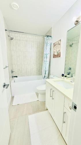 a white bathroom with a tub and a toilet and a sink at Fairway Retreat Chilliwack in Chilliwack