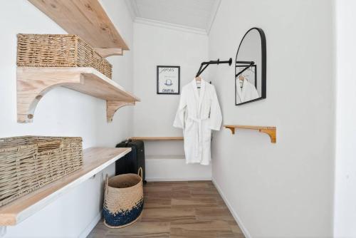 a hallway with white walls and a staircase with a mirror at The Tide & Seek House in Cape Town