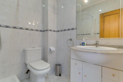 a white bathroom with a toilet and a sink at Esfera I Calm Stay With Parking & Workspace in Caniço