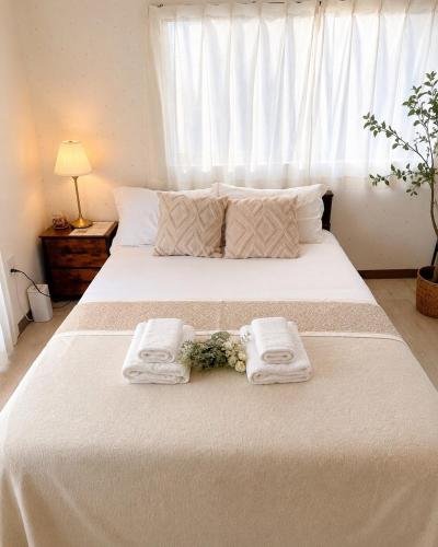a bedroom with a large white bed with towels on it at Lee house 佳 別荘 一戸建て貸切の宿 in Osaka