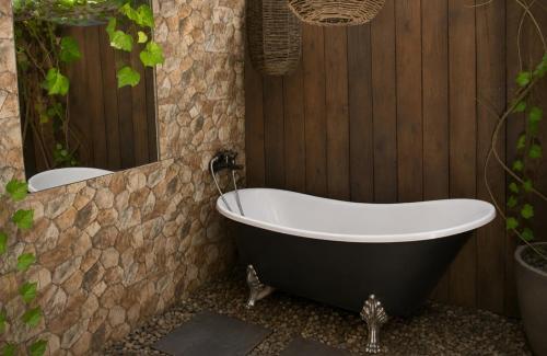 a bath tub in a bathroom with a stone wall at The Bliss Boutique in Louis Trichardt