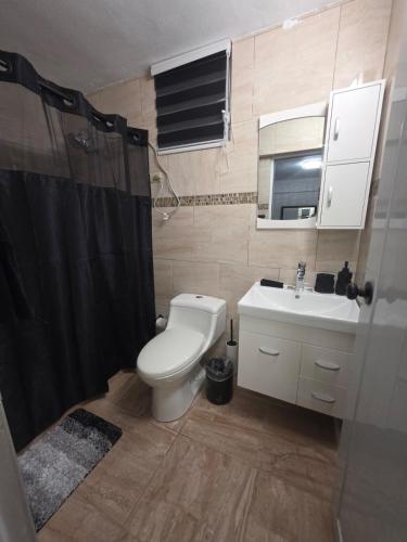 a bathroom with a toilet and a sink and a shower at Black House in Anasco
