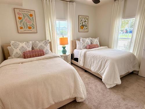 two beds in a bedroom with two windows at StarkVilla - The Perfect Location! in Starkville