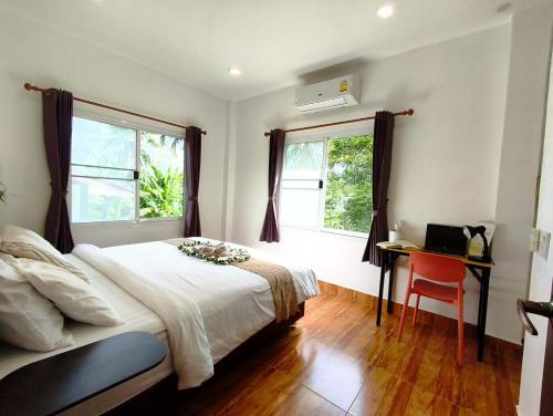 a bedroom with a bed and a desk and two windows at Mangrove Beach Houses in Srithanu