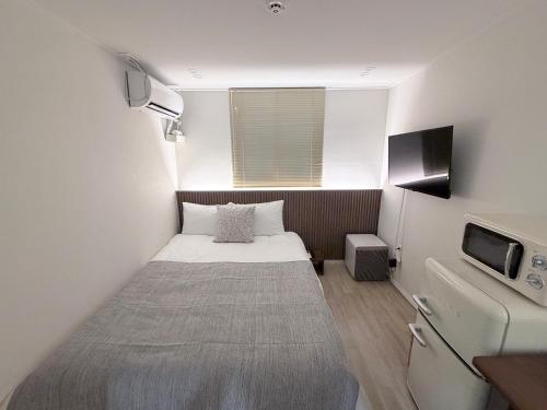 a small room with a bed and a television at 303 Stayonyou Gocheok Dome Hongdae Subway 3Min in Gwangmyeong