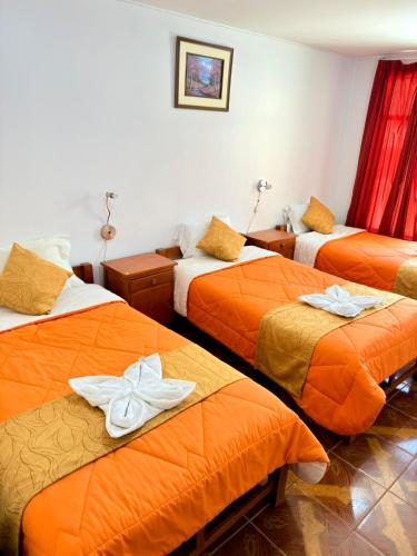 a hotel room with three beds with towels on them at Sunrise Guest House in Huaraz