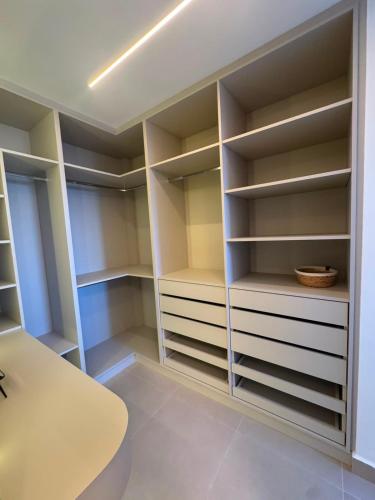 a walk in closet with white shelves and a table at Studio Mandarim Campolim in Sorocaba