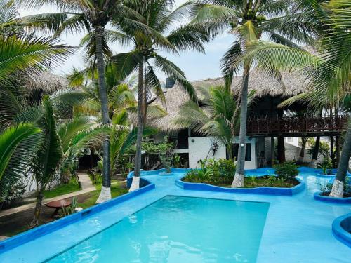 a pool with palm trees in front of a resort at Marbella Eco Lodge in Monterrico