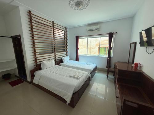 a bedroom with two beds and a window at White Castle in Siem Reap