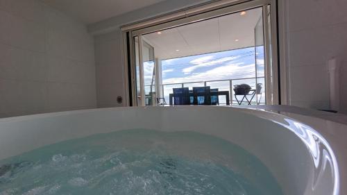 a bath tub in a bathroom with a large window at Coco Resort Futtsu in Futtsu