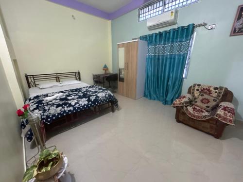 a bedroom with a bed and a chair at JAJABAR Homestay in Dum Duma