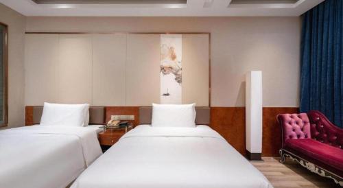 a hotel room with two beds and a red chair at Oriental Glory Hotel in Dongguan