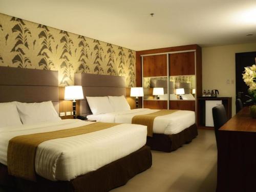a hotel room with two beds and a desk at GT Hotel Bacolod in Bacolod