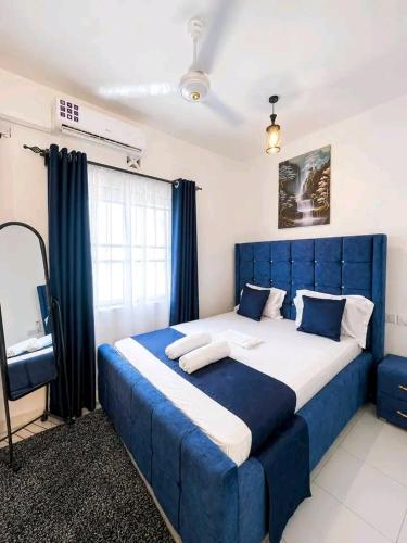 a bedroom with a blue bed and a television at JKIA Prestige kenya in Nairobi