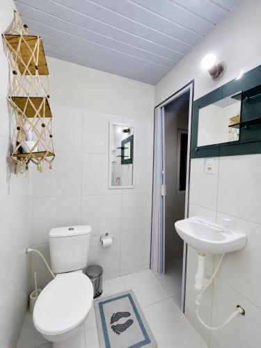 a white bathroom with a toilet and a sink at Chalé Rosani in Pipa