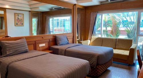 a room with two beds and a couch and a window at New Siya in Maha Sarakham