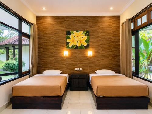 two beds in a room with two windows at mascot hotel senggigi in Senggigi