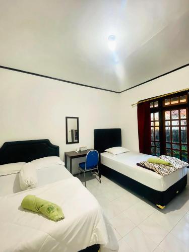 a bedroom with two beds and a desk and a chair at Mawar Bed and Breakfast in Bajawa