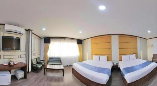 a bedroom with two beds and a desk and a television at Horizon Hotel in Olongapo
