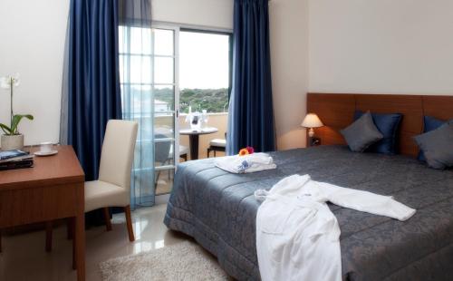 um quarto de hotel com uma cama, uma secretária e uma janela em Casa da Praia em Ferragudo