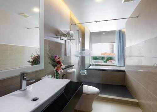 a bathroom with a sink and a toilet and a window at Aiyara Grand Hotel in Pattaya South