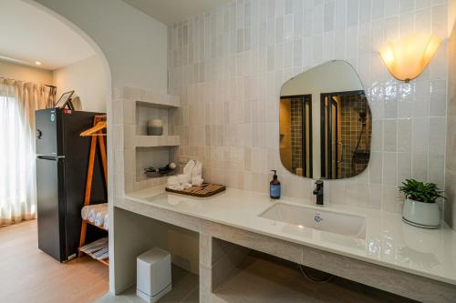 a bathroom with a sink with a mirror and a refrigerator at Sea Salt Stay Samui in Nathon
