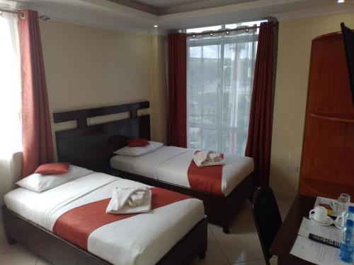 a hotel room with two beds and a window at Claire de Lune Moonlight Hotel in Nakuru
