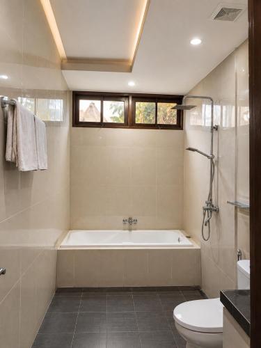 a bathroom with a bath tub and a toilet at mascot hotel senggigi in Senggigi