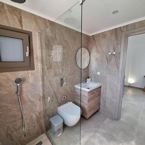 a bathroom with a shower and a toilet and a sink at Kipos Suites Nidri Lefkada in Nydri