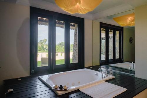 a large bath tub in a room with windows at Anhera Suite Ubud in Ubud