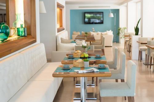 een eetkamer met tafels en stoelen en een bank bij Hotel Prestigio in Milano Marittima